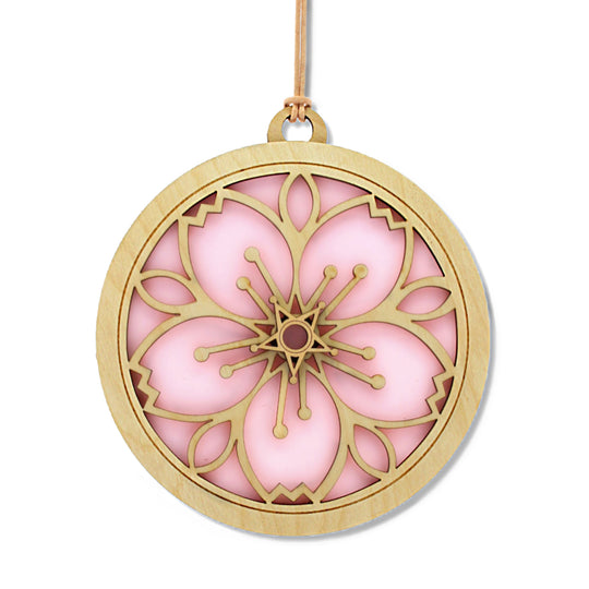 Stained_glass_and_wood_suncatcher_window_ornament_in_cherry_blossom_design_cut_out. Glass_is_pink_color_and_light_color_wood_with_design_cut_out_on_both_sides.